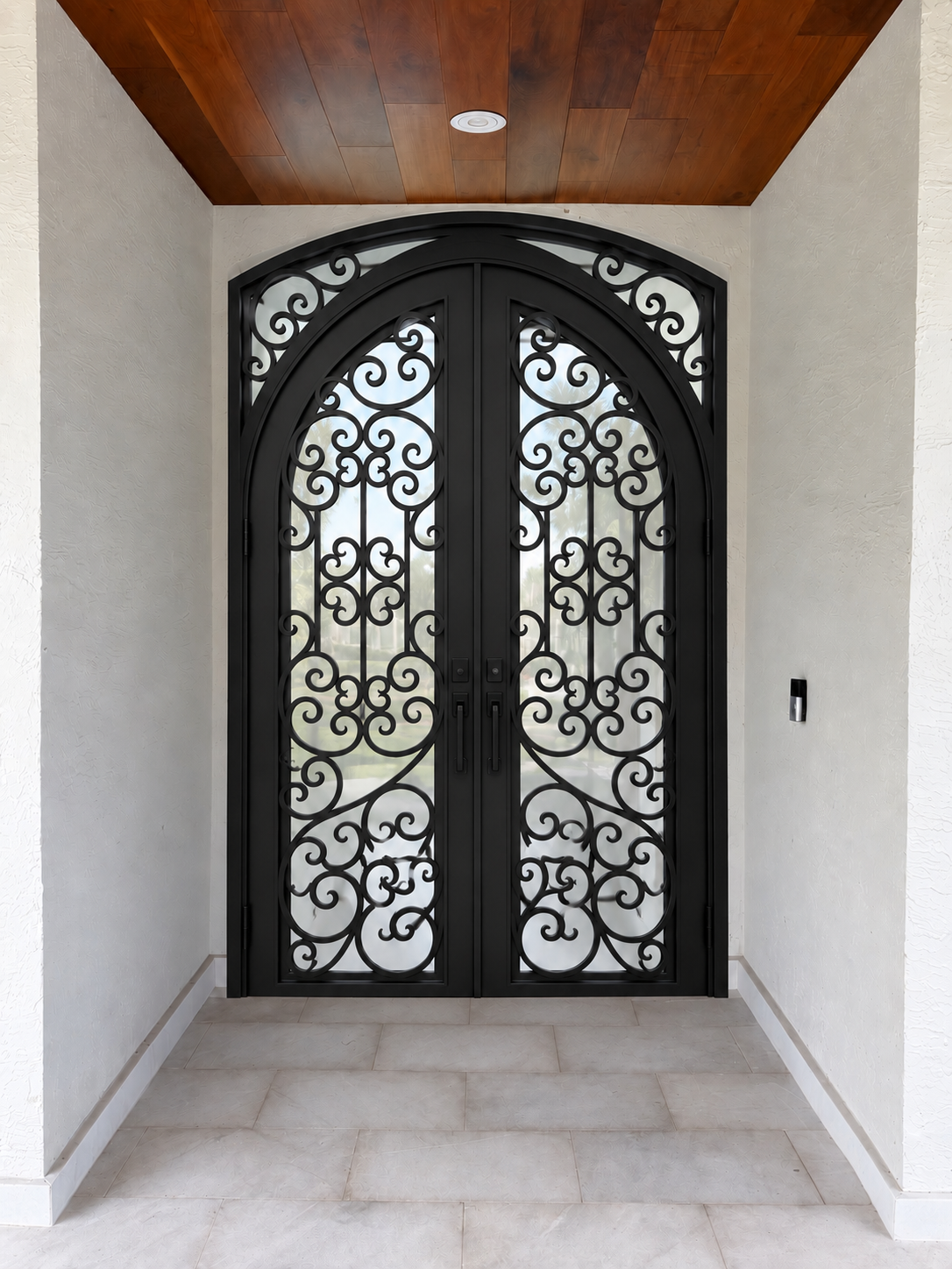 Arched traditional iron double door with symmetrical decorative scrollwork
